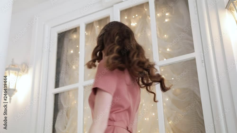 A young girl is spinning in a pink dress against the background of a high window with yellow garlands. The sexy girl is smiling and laughing. Timelapse 1920x1080 A young girl is spinning in a pink dress against the background of a high window with yellow garlands. The sexy girl is smiling and laughing. Timelapse 1920x1080