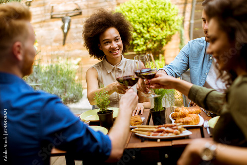 Cheerful young people have lunch in the courtyard and toasting with red wine © BGStock72