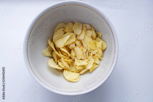 Potato chips in a plate on a white background. A white plate with tasty potato chips.