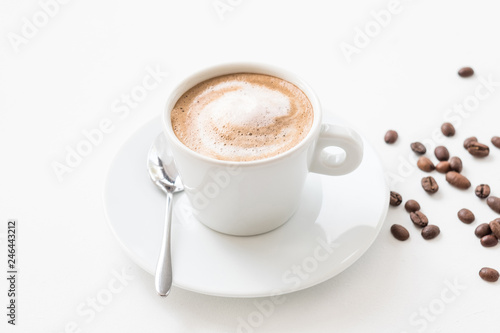 Morning coffee lifestyle. Hot invigorating drink. Latte cup with milk foam and beans on white background.