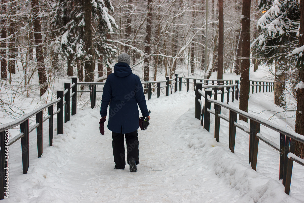 person walking on a snow-covered road in the woods. winter frosty weather. people are dressed in warm clothes.