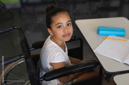 High angle view of disabled schoolgirl looking at camera and