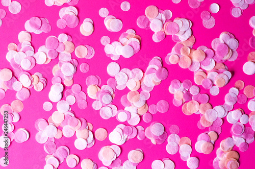 Abstract pink background with multicolored round confetti.