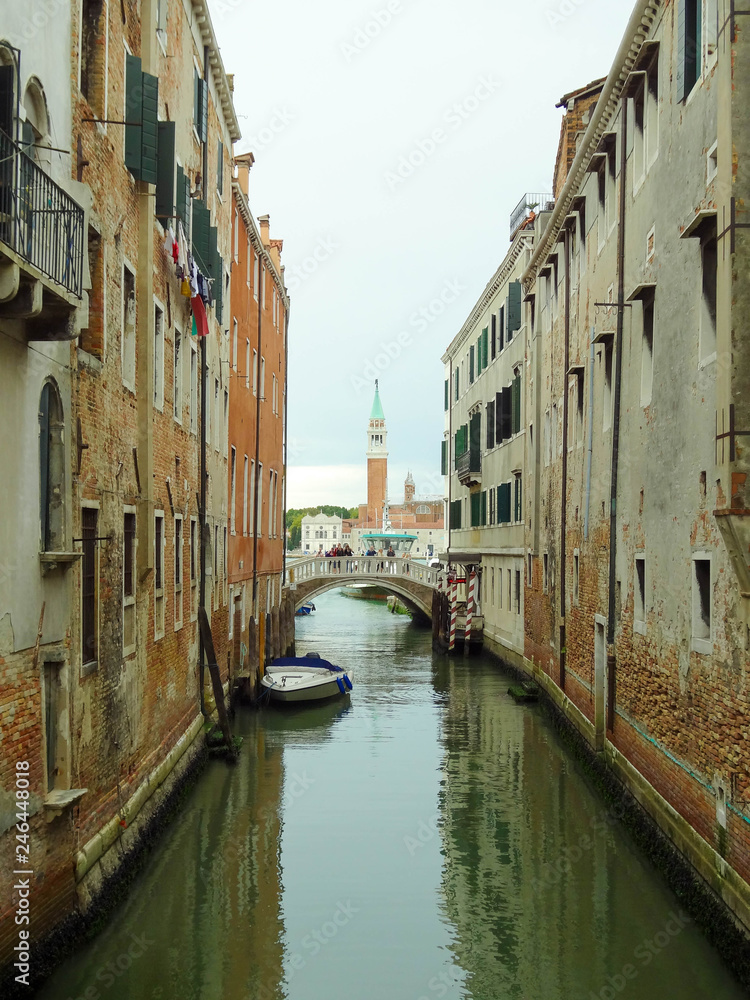 View to one of the venetian bridge with rio del greci and bell tower of  basilica di San Giorgio Maggiore on the background, Venice, Italy