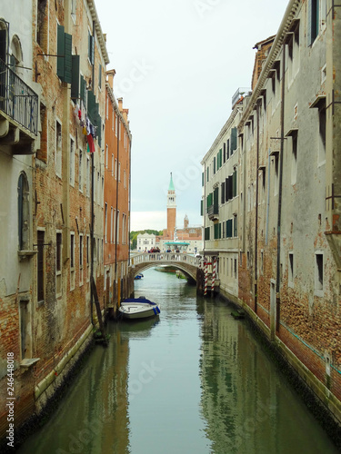 View to one of the venetian bridge with rio del greci and bell tower of basilica di San Giorgio Maggiore on the background, Venice, Italy