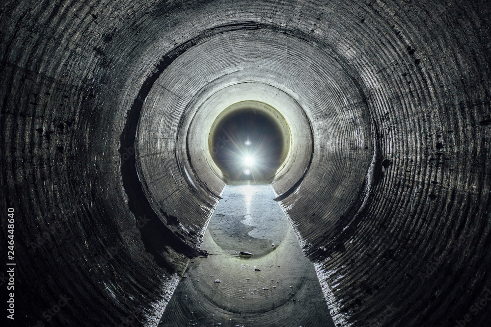 Flooded round underground drainage sewer tunnel with dirty sewage water