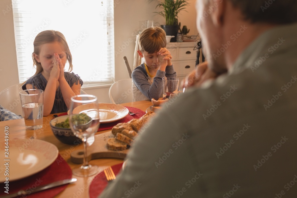 Family praying before having food on dining table