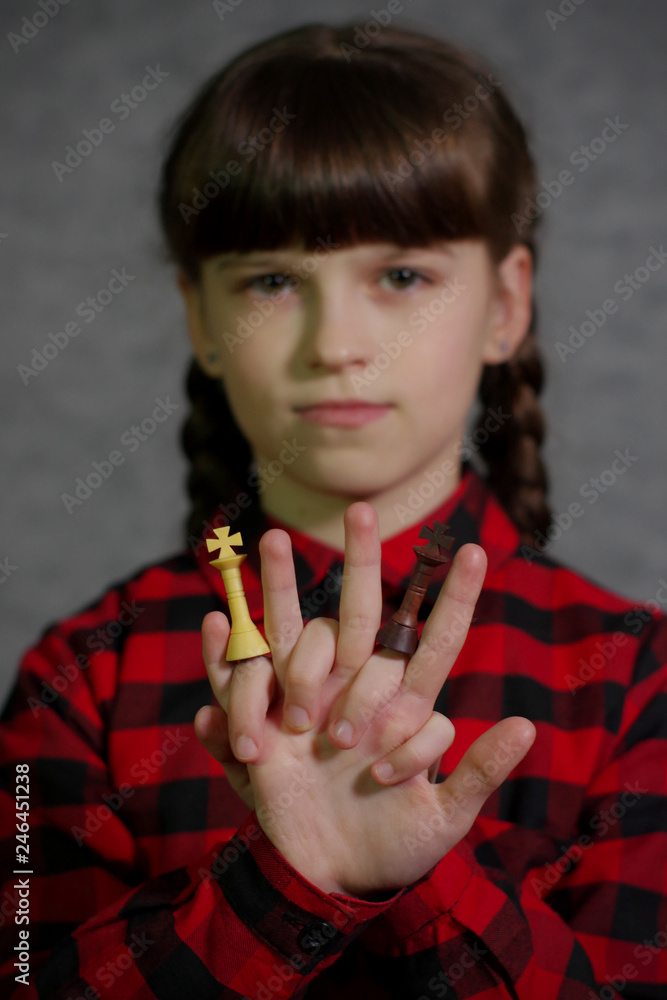 Obraz premium Girl holding chess pieces in front of her. Black and white chess king in the hands of a girl