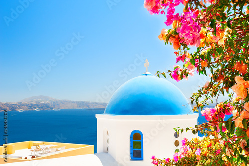 Santorini island, Greece. Traditional greek church with blue dome and tree with pink flowers