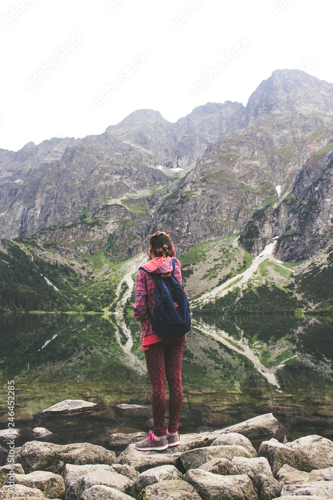 Young woman on shore of mountain lake. The back of girl against background of mountains. Woman, Sea eye Young woman on shore of mountain lake. The back of girl against background of mountains. Woman, Sea eye