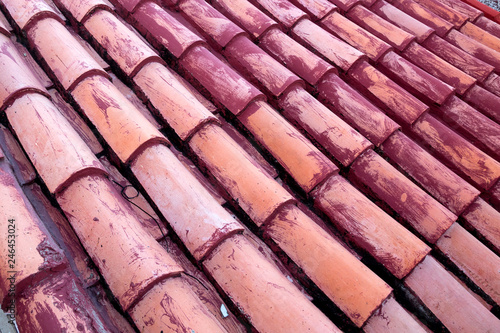 New terracotta tiles laid on a roof, partially painted red.
