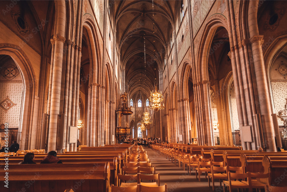 People praying inside the 13th century catholic Uppsala Cathedral in gothic style