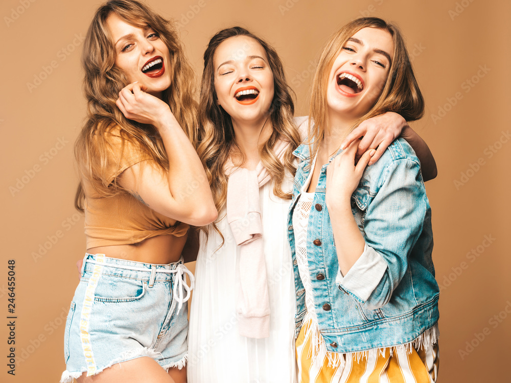 Three young beautiful smiling hipster girls in trendy summer casual clothes. Sexy carefree women posing on golden background. Positive models going crazy Three young beautiful smiling hipster girls in trendy summer casual clothes. Sexy carefree women posing on golden background. Positive models going crazy