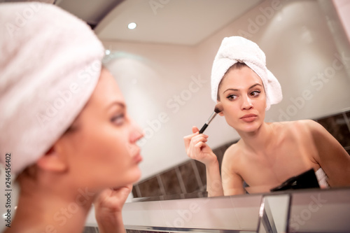 Smiling woman in bathroom applying makeup