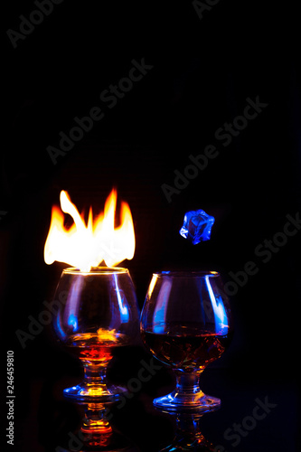 Two Glasses with burning alcohol and ice on dark background
