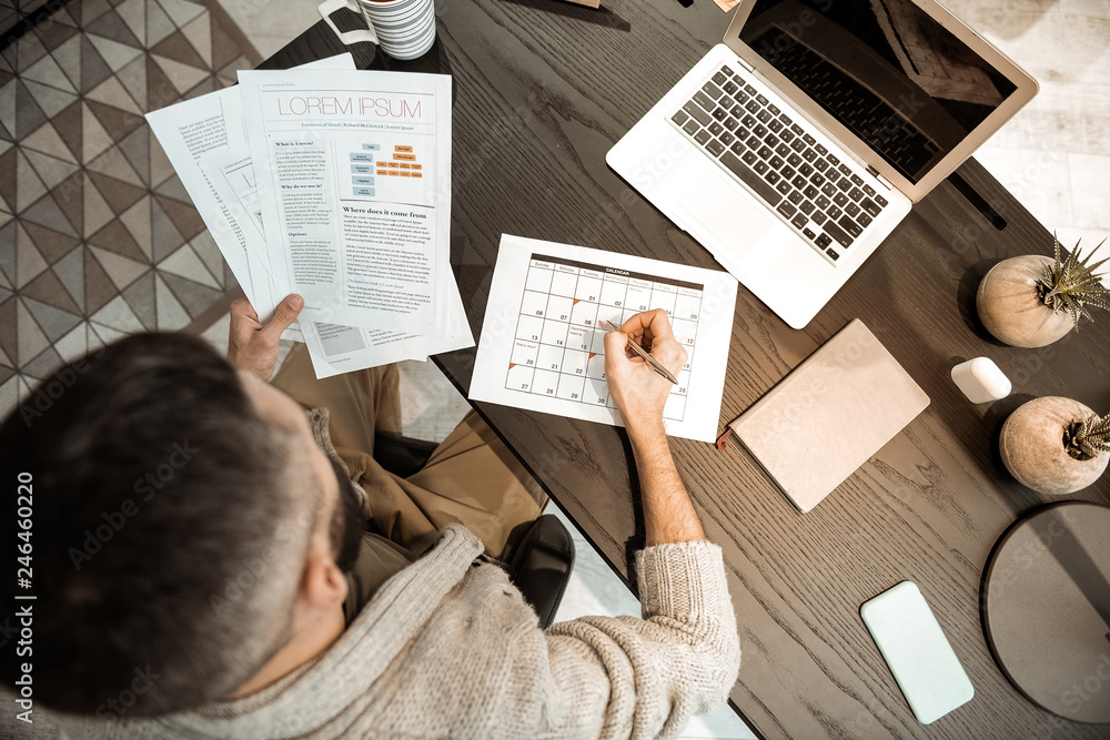 Obraz premium Concentrated dark-haired man being busy with documents and schedule