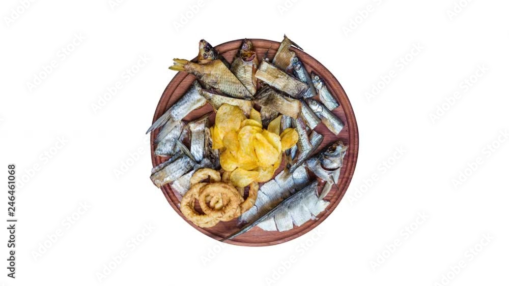 Beer snacks set. Salted, dried fish, squid rings and potato chips, rotate on the cutting board. Isolated on the white background. Beer snacks set. Salted, dried fish, squid rings and potato chips, rotate on the cutting board. Isolated on the white background.