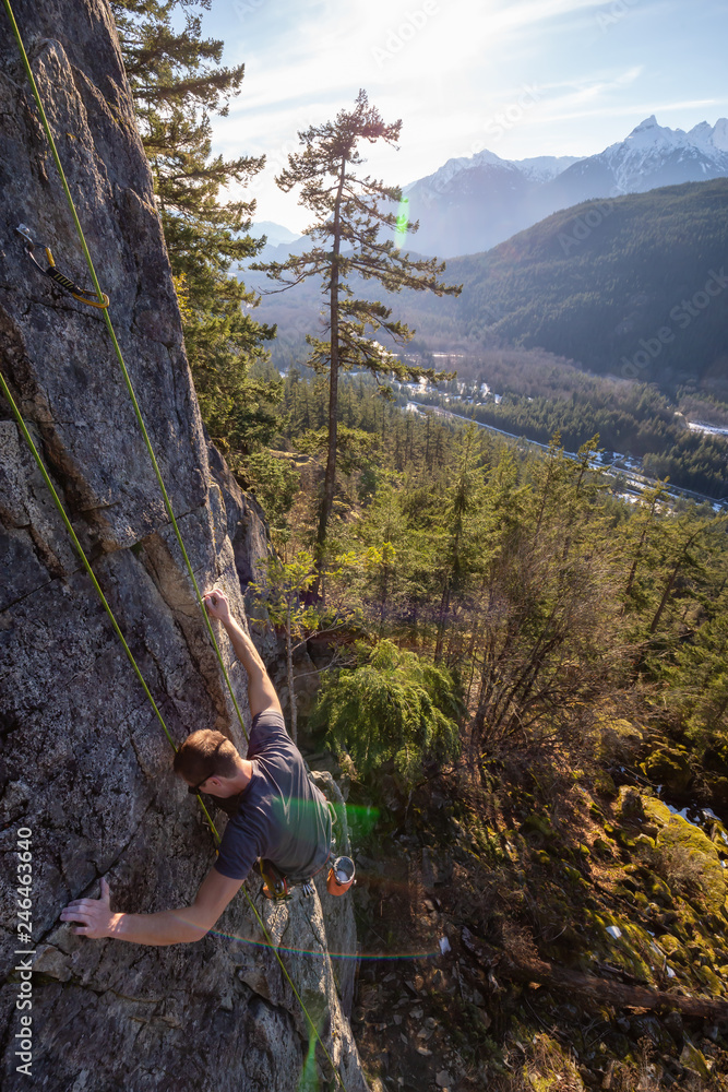 Male Rock climber climbing on the edge of the cliff during a sunny winter sunset. Taken in Area 44 near Squamish and Whistler, North of Vancouver, BC, Canada.