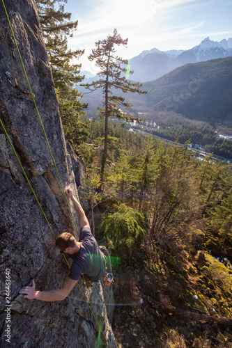 Male Rock climber climbing on the edge of the cliff during a sunny winter sunset. Taken in Area 44 near Squamish and Whistler  North of Vancouver  BC  Canada.