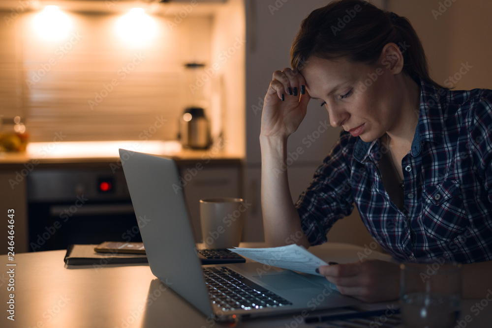 Serious woman reading her financial bills at home Serious woman reading her financial bills at home