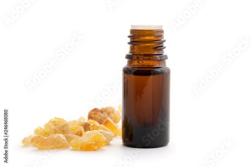 A bottle of frankincense essential oil with frankincense resin on a white background photo