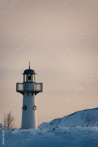 White lighthouse on a winter landscape on a sunset. Vertical view