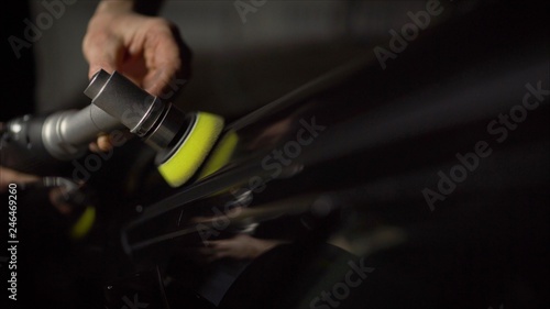 Car detailing - Hands with orbital polisher in auto repair shop. Selective focus. Car polishing and LCP correction