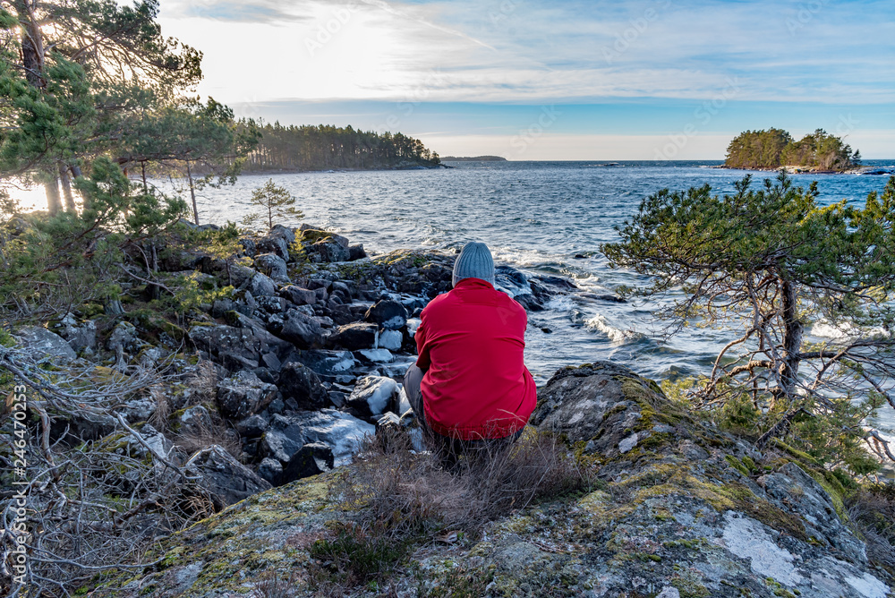 man in red jacket overlooking a lake
