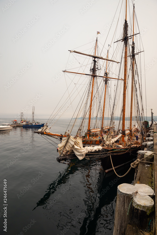 Obraz premium Port Hardy, Vancouver Island, BC, Canada - August 20, 2018: Wooden sailboat parked at a marina during a foggy summer day.