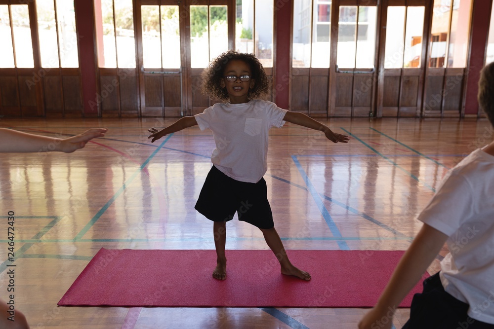 Fototapeta Schoolgirl doing yoga on a yoga mat in school