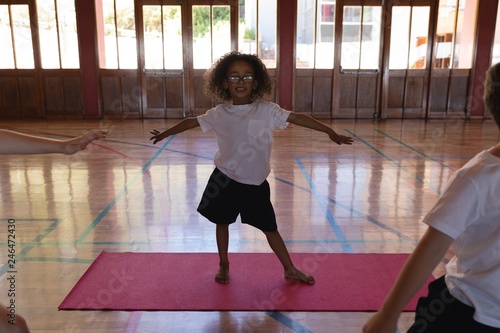 Fotografija Schoolgirl doing yoga on a yoga mat in school