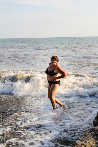 Woman in a swimsuit bathes in the sea, big waves