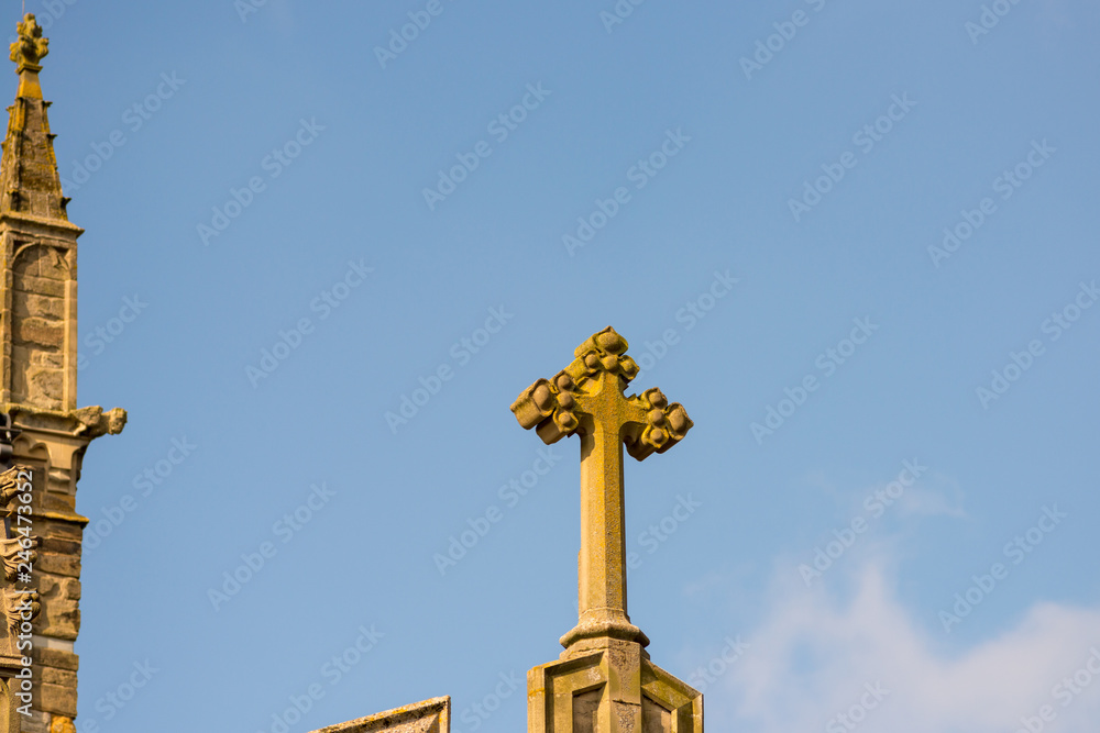 stone cross on church roof with blue skies in background stone cross on church roof with blue skies in background