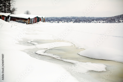 Frozen river covered with ice and snow in the village.