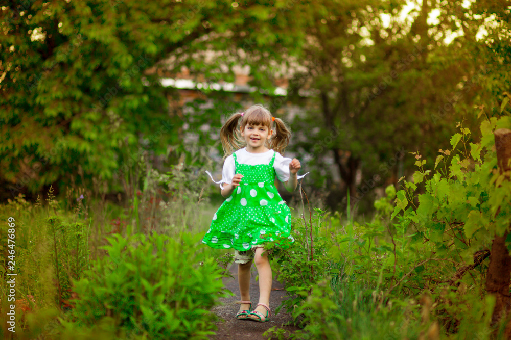 Little girl walk in green garden in summer day Little girl walk in green garden in summer day