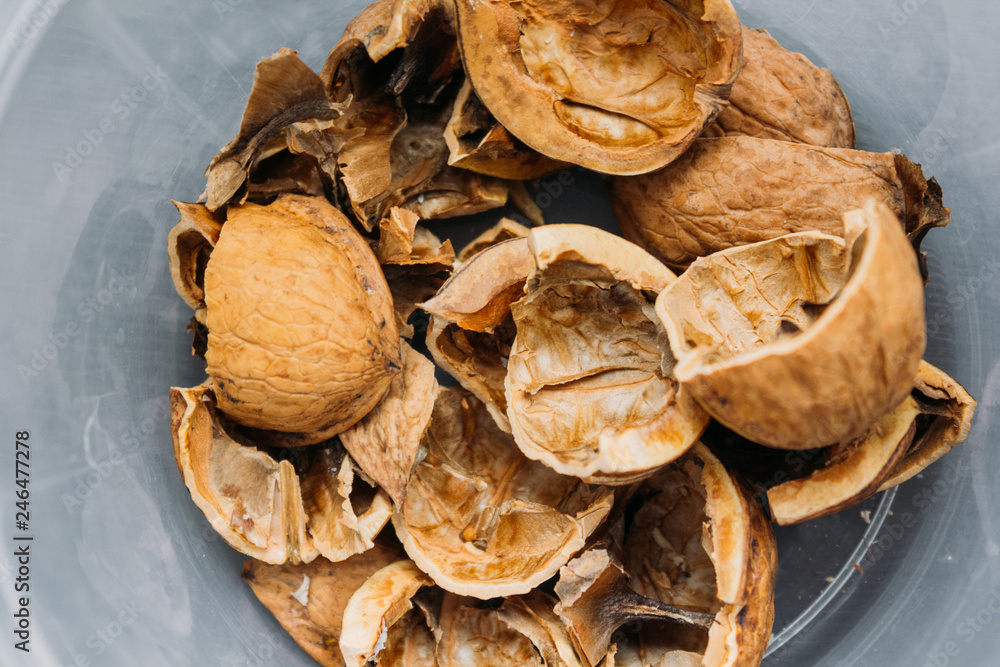 Fototapeta premium Top view of cracked walnuts shell on wooden background.
