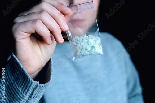 hand holds packet with white narcotic - cocaine, meth or another drug photo