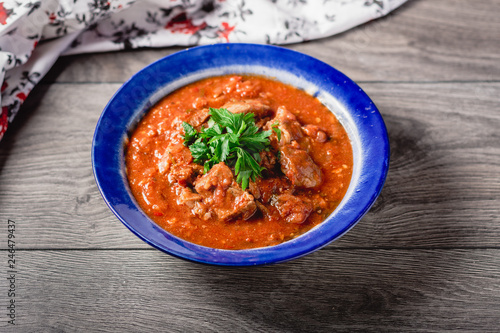 veal meat in tomato sauce with onion, garlic, chili peper on the wooden background. boiled meat and fresh tomato horizontal view