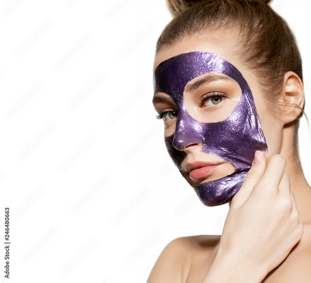 Portrait of attractive young female removing clay face mask and looking at camera. Skincare wellness and cleansing concept. Cute girl moisturizing skin on white background