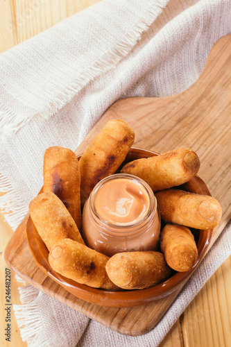 Top view of Latin-American appetizers called Tequeños made of fried corn filled with cheese with a pink sauce photo