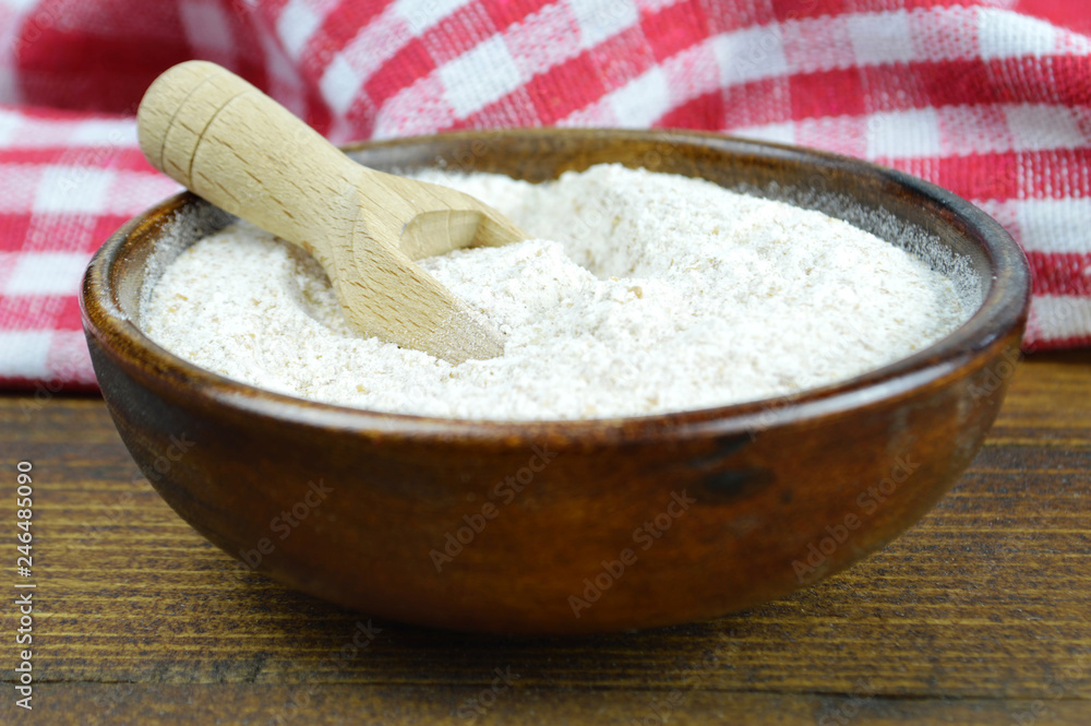 Whole wheat flour in wooden bowl, wooden background Whole wheat flour in wooden bowl, wooden background