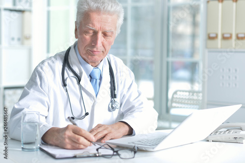 confident senior male doctor with stethoscope working in office