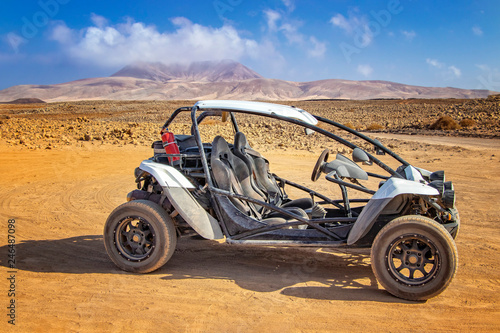 White buggy in stone and sandy desert on volcanic island photo