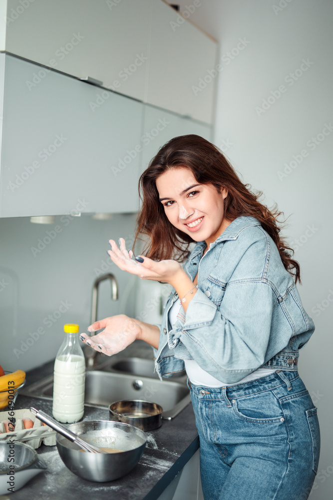 Girl cooking pancakes in the kitchen, home with flowers, eggs, fruits on the table. Girl cooking pancakes in the kitchen, home with flowers, eggs, fruits on the table.