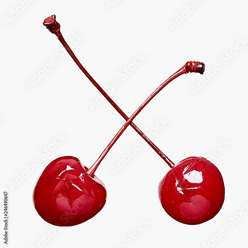 Two maraschino cherries on a light grey background
