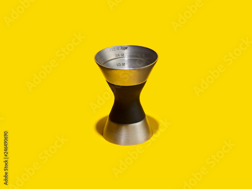Double jigger cocktail measure on a yellow background
