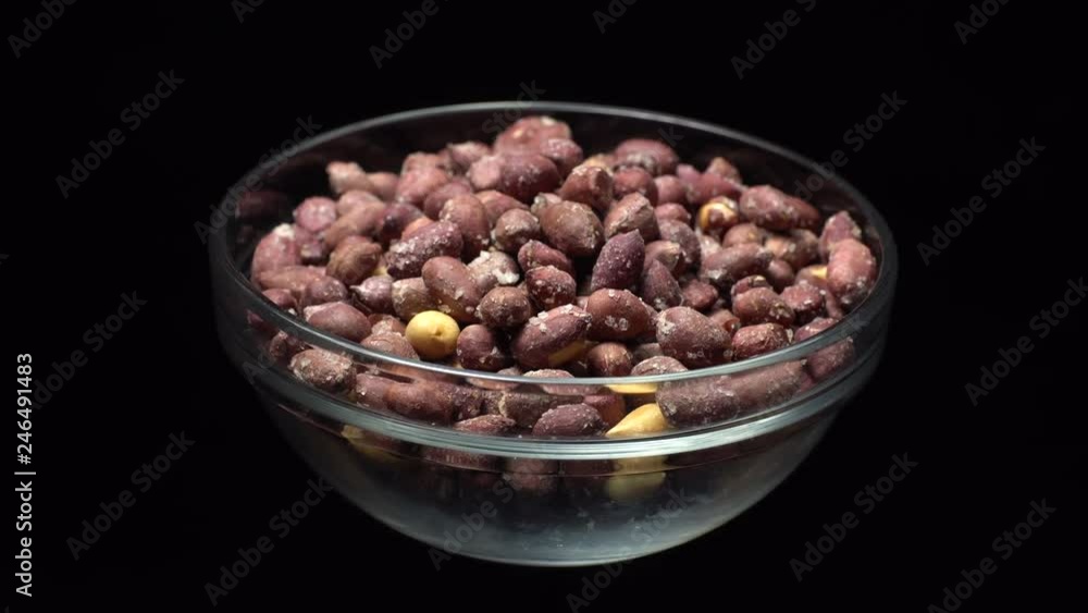 Raw unpeeled peanuts fried with salt. Rotation. Snack closeup. Peanuts in a bowl. Selective focus. black background. Studio shot. Healthy food concept. Raw unpeeled peanuts fried with salt. Rotation. Snack closeup. Peanuts in a bowl. Selective focus. black background. Studio shot. Healthy food concept.
