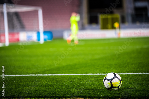 Football, soccer photo. Ball on the green grass and football goalkeeper in background