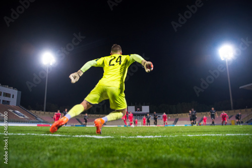Goalkeeper catching the ball, night football match, stadium, spotlight