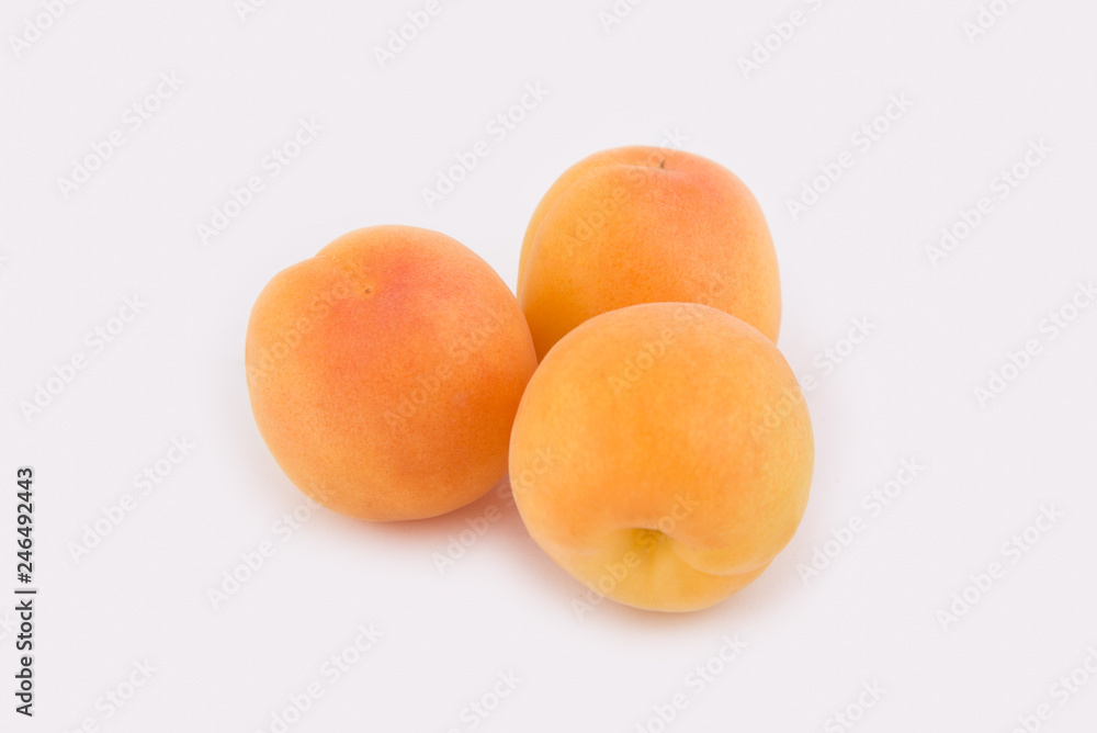 Three apricots lie side by side isolated on white background. Close-up photo Three apricots lie side by side isolated on white background. Close-up photo